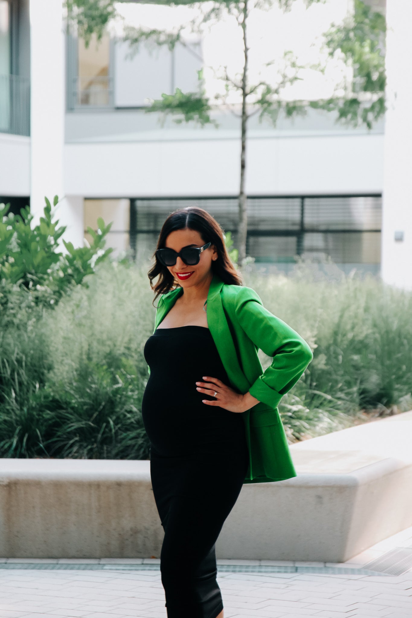 Schwangere Frau im schwarzen Umstands-Tube Kleid und grünem Blazer
