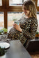 Schwangere Frau im Leoparden Umstandskleid beim Teetrinken