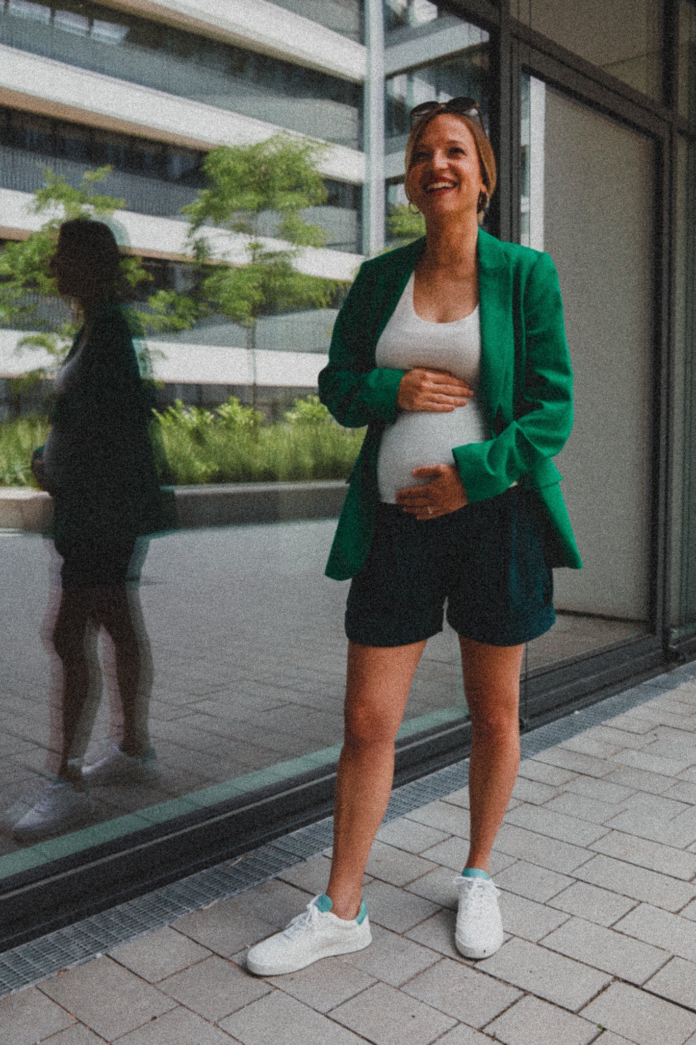 Blonde Frau mit grünem Schwangerschaftsblazer