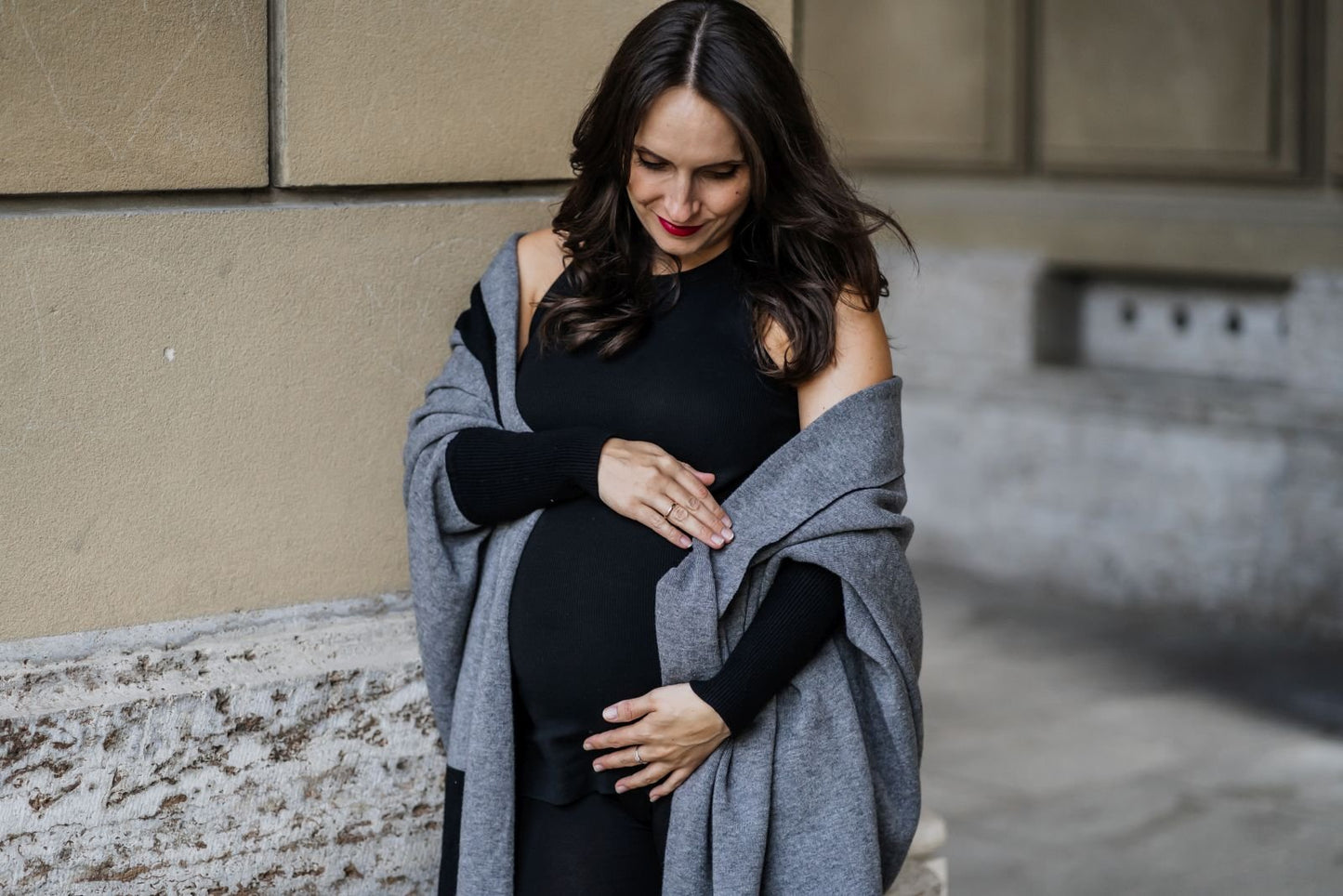 Frau mit Babybauch schwarzem Kleid und grauem Umstandsschal
